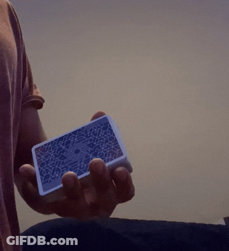 Person Holding Blue Playing Card With Geometric Pattern GIF