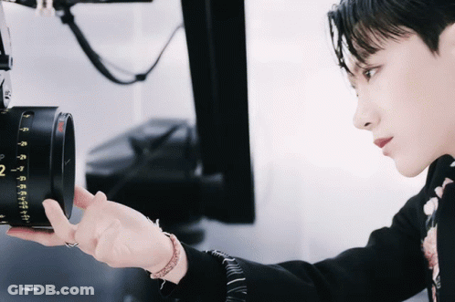 Person Holding Camera With Number 2 On Lens GIF