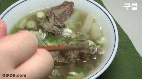 Person Holding Chopsticks Over Bowl Of Soup With Meat And Onions GIF
