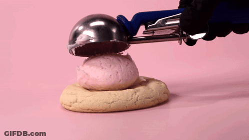Person Holding Cookie With Pink Frosting GIF