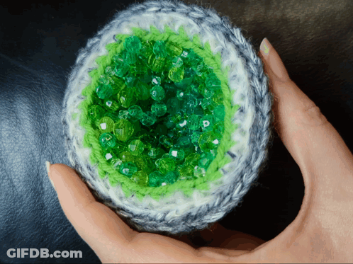 Person Holding Crocheted Object With Green Beads GIF
