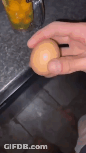 Person Holding Egg In Front Of Orange Juice GIF