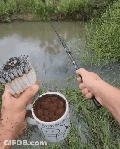 Person Holding Fishing Rod Next To Mug Saying As Vezes Da Vitoria GIF