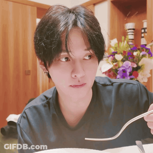 Person Holding Fork In Front Of Flower Arrangement GIF