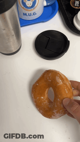 Person Holding Glazed Donut And M.U.G. Mug GIF