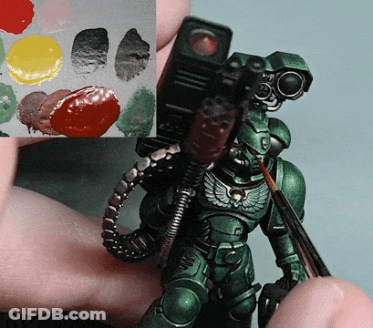 Person Holding Green Robot And Brush Next To Paint Palette GIF