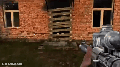 Person Holding Gun In Front Of Brick Building GIF