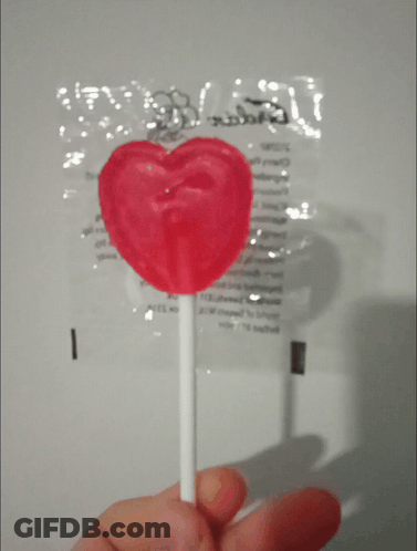 Person Holding Heart Lollipop In Front Of Candy Bag GIF