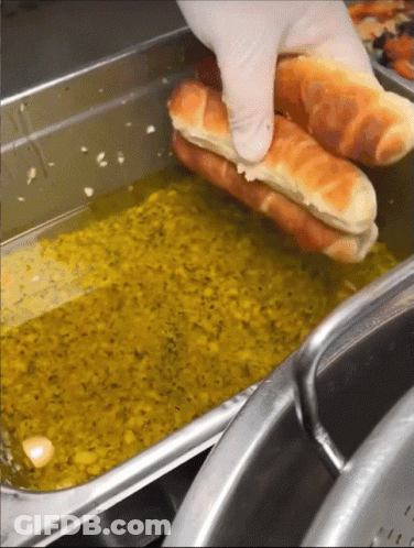 Person Holding Hot Dog Over Oil GIF