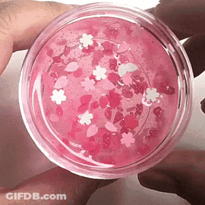 Person Holding Jar Of Pink Slime With Flowers GIF