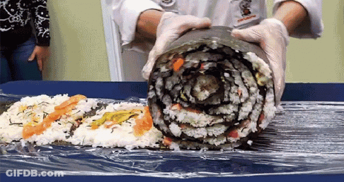 Person Holding Large Sushi Roll With Chef's Name GIF