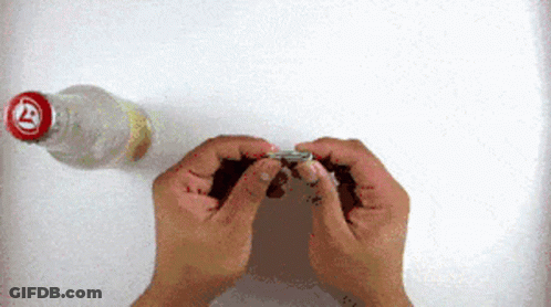 Person Holding Paper In Front Of Bottle With Letter T GIF