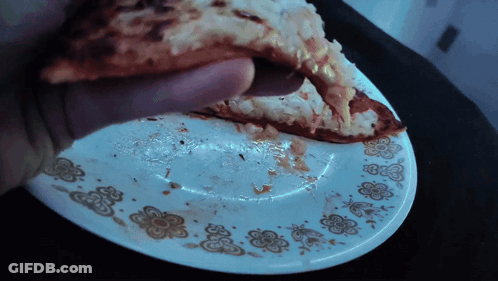 Person Holding Pizza Slice Over Plate With Flowers GIF