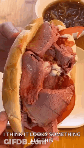 Person Holding Roast Beef Sandwich With Tomatoes And Cheese GIF