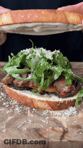 Person Holding Sandwich With Meat And Lettuce GIF