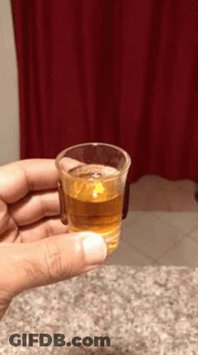 Person Holding Shot Glass With Red Curtain Background GIF