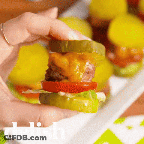 Person Holding Small Hamburger With Pickles And Cheese GIF