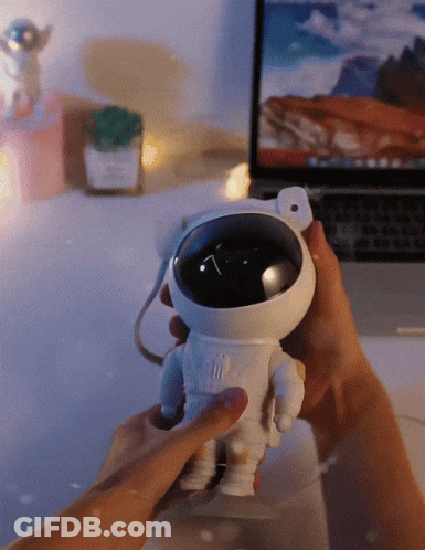 Person Holding Toy Astronaut In Front Of Laptop GIF