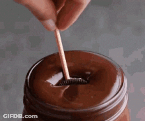 Person Holding Wooden Toothpick In Chocolate Sauce GIF