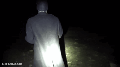 Person In Black Coat Standing In Dark GIF