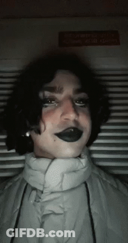 Person In Black Lipstick And White Jacket Looking At Camera GIF