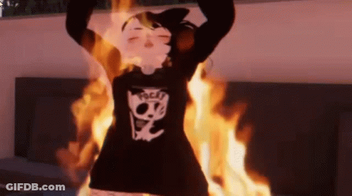 Person In Black Sweater With Skull Standing In Front Of Fire GIF