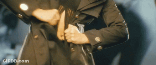 Person In Black Trench Coat Holding Purse GIF