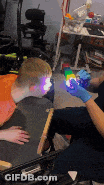 Person In Blue Gloves Holding Rainbow Object In Front Of Child GIF