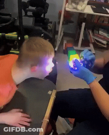 Person In Blue Gloves Holding Rainbow Toy GIF