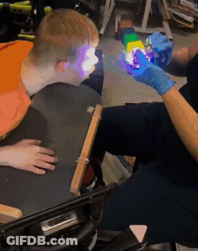 Person In Blue Gloves Holding Rainbow Toy GIF