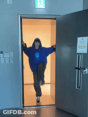 Person In Blue Jacket Standing In Dance Studio Doorway GIF