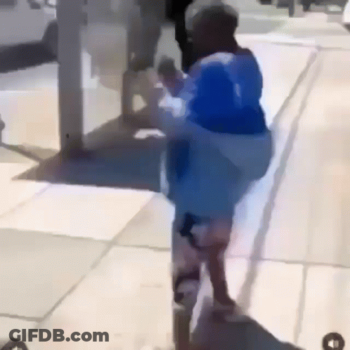 Person In Blue Jacket Walking Down Sidewalk GIF