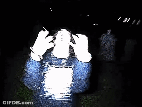 Person In Blue Sweater Covering Face In Dark GIF