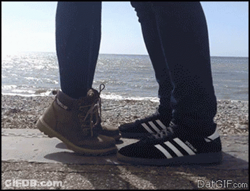 Person In Caterpillar Boots Next To Adidas Shoes GIF