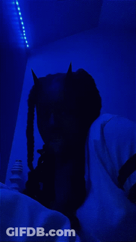 Person In Devil Costume Lying On Bed With Blue Light GIF