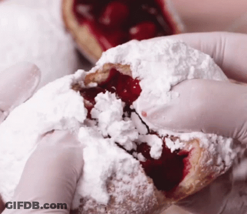 Person In Gloves Holding Pastry With Powdered Sugar And Cherry Filling GIF