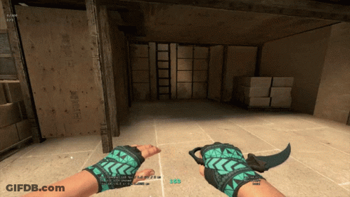 Person In Green Gloves Holding Knife In Warehouse GIF