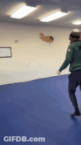 Person In Green Jacket Standing On Blue Mat GIF