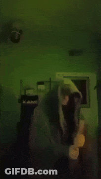 Person In Hoodie Standing In Dark Room With Green Background GIF