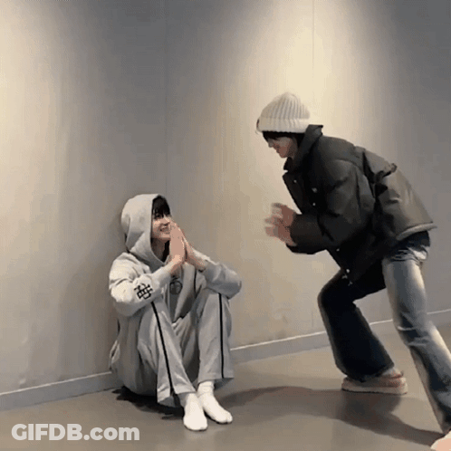 Person In Hoodie With Chinese Symbol Squatting Next To Another GIF