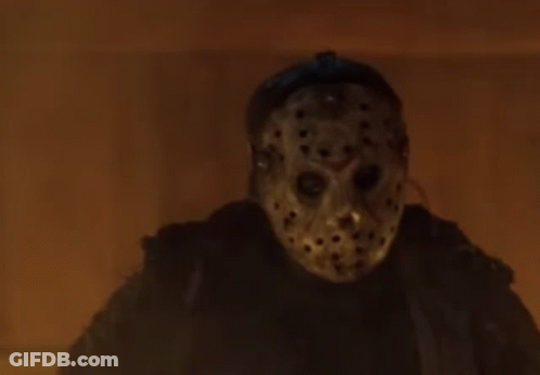 Person In Jason Voorhees Mask Standing In Front Of Fire GIF