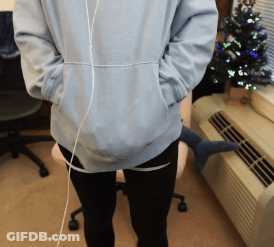 Person In Light Blue Hoodie And Black Pants In Front Of Christmas Tree GIF