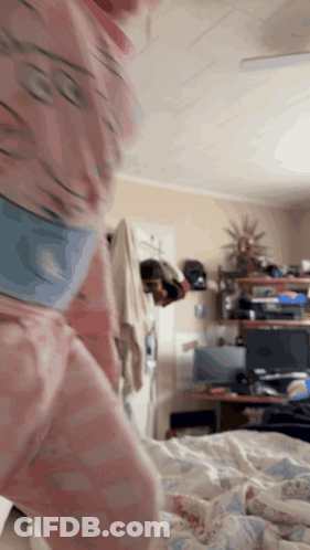Person In Pink Pajamas Standing In Bedroom GIF