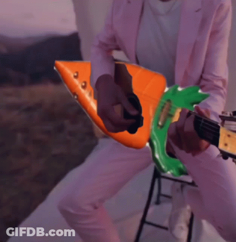 Person In Pink Suit Playing Orange And Green Guitar GIF