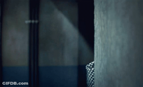 Person In Plaid Shirt Standing In Dark Room GIF