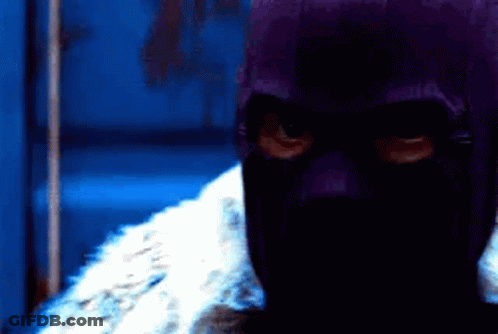 Person In Purple Mask Standing In Dark Room GIF