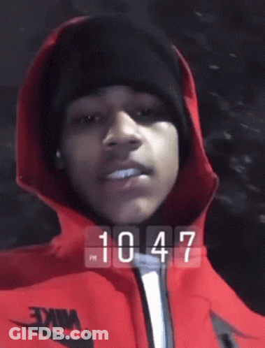 Person In Red Jacket And Black Beanie At 10:47 GIF