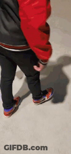 Person In Red Jacket And Black Jeans Standing On Concrete GIF