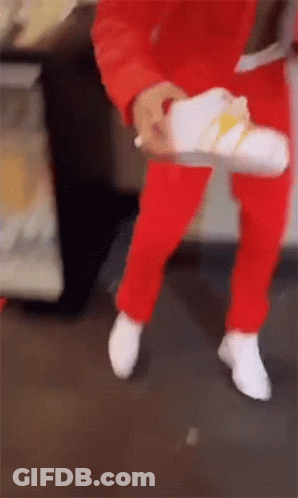 Person In Red Pants Holding White Shoe GIF