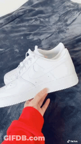 Person In Red Sweater Holding White Nike Sneakers GIF